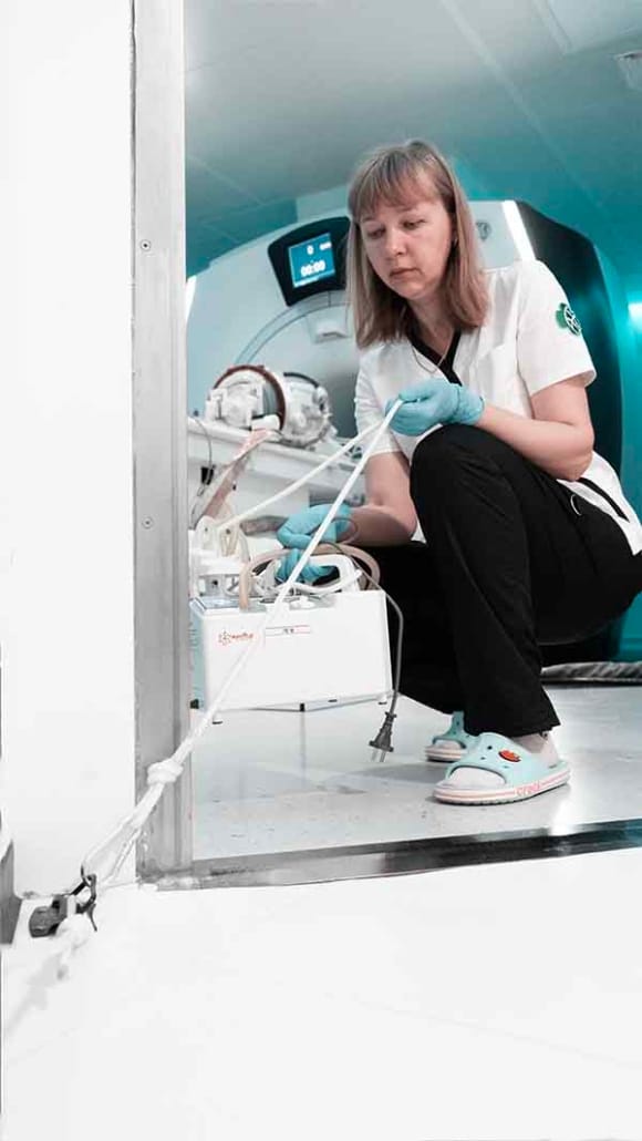 Nurse Yulia Mukhina secures the medical aspirator to prevent it from being brought into the MRI room at a dangerous distance if needed in an emergency situation  | VS Buzaev International MRgFUS Medical Treatment Centre Nurse Yulia Mukhina secures the medical aspirator to prevent it from being brought into the MRI room at a dangerous distance if needed in an emergency situation